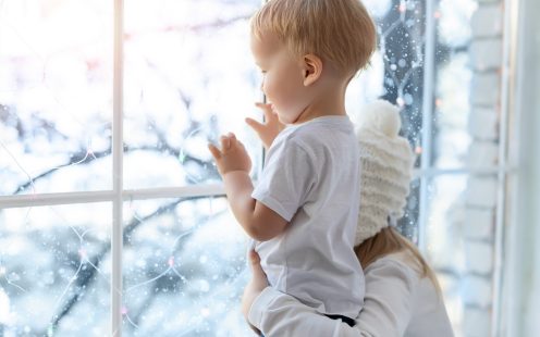 Two cute adorable little blond cauasian children siblings stay near window and looking outside waiting for snow, wonders and miracle at christmas holidays. Stay home at covid-19 pandemic lockdown