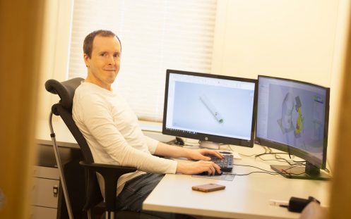 En person sitter ved en kontorpult foran en PC med hendene på tastaturet.