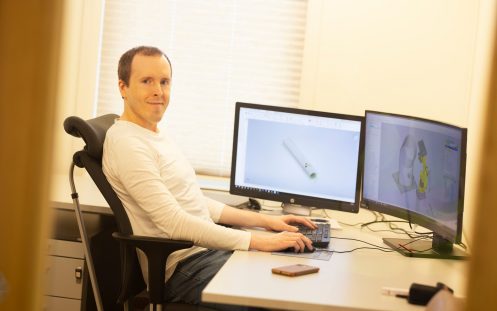 En person sitter ved en kontorpult foran en PC med hendene på tastaturet.