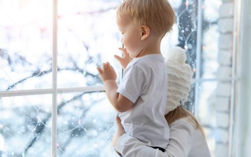 Two cute adorable little blond cauasian children siblings stay near window and looking outside waiting for snow, wonders and miracle at christmas holidays. Stay home at covid-19 pandemic lockdown