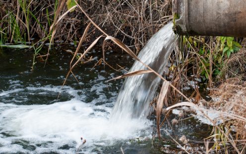 Polluted water. Concrete pipe transporting the poluted river in to a small pound.